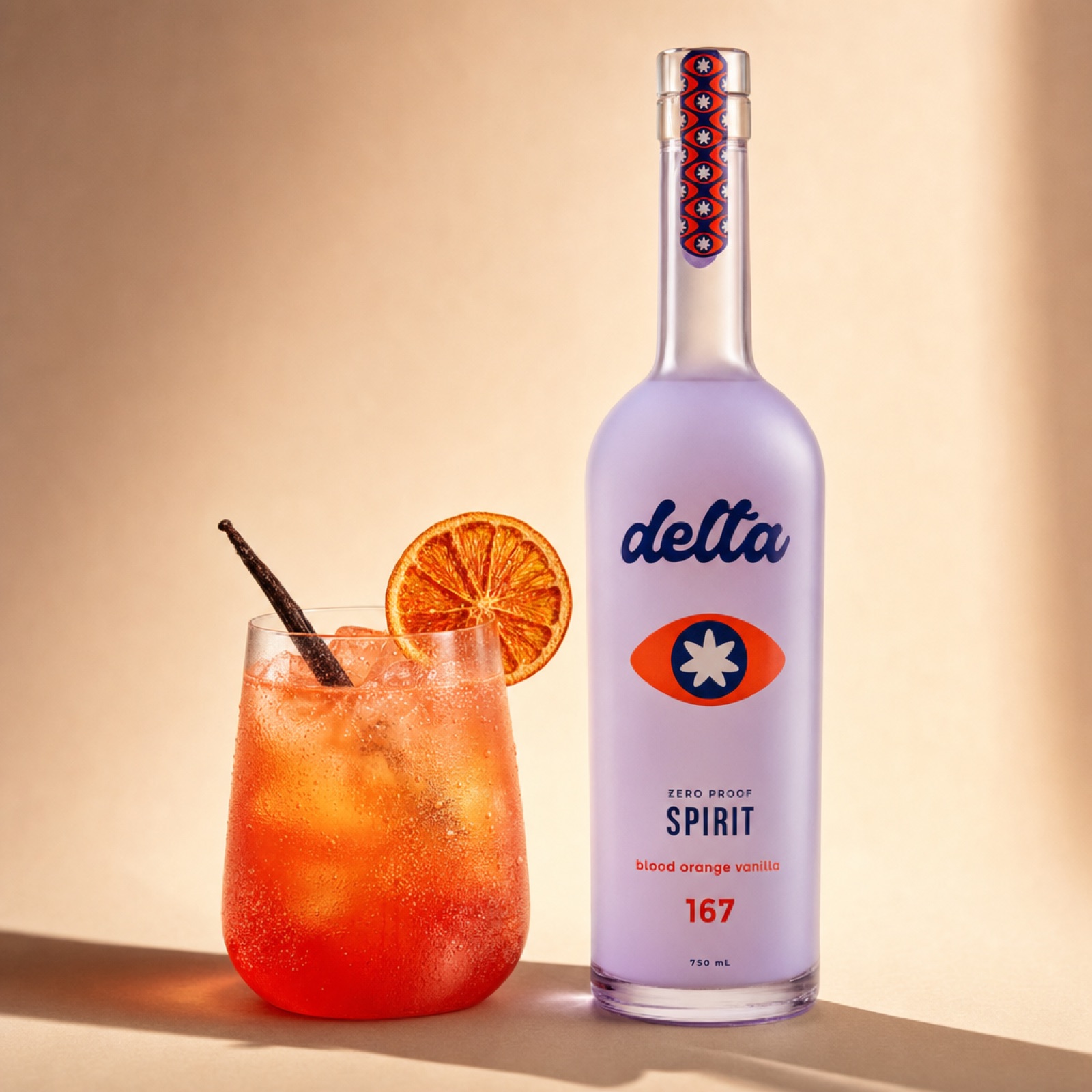 A blood orange spritz over ice with a dried orange wheel and vanilla bean stir stick, alongside the Delta zero-proof Spirit bottle, tight comp on a warm beige background.