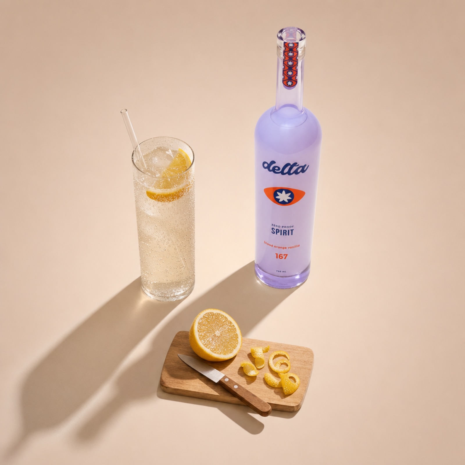 A tall highball of citrus soda over ice with a lemon wedge, the Delta zero-proof Spirit bottle alongside on a wooden cutting board with a half lemon and lemon peel curls.