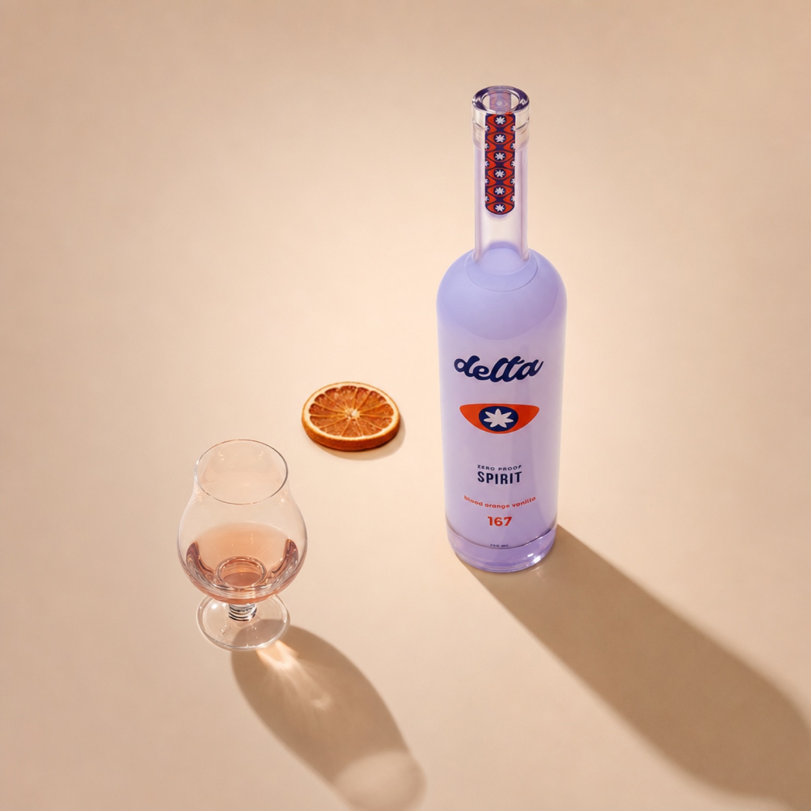 A small snifter holding a neat pour of the Spirit, the bottle alongside with a single dried blood orange slice.